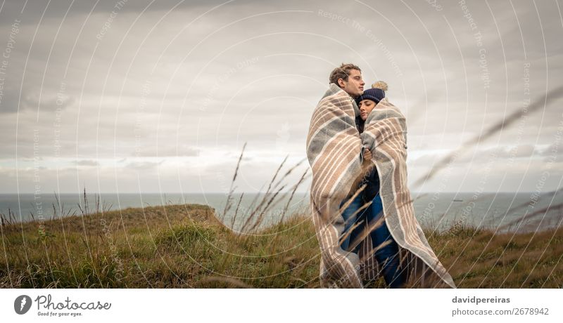 Young couple embracing outdoors under blanket in a cold day Lifestyle Beautiful Calm Ocean Winter Mountain Woman Adults Man Couple Nature Landscape Sky Clouds