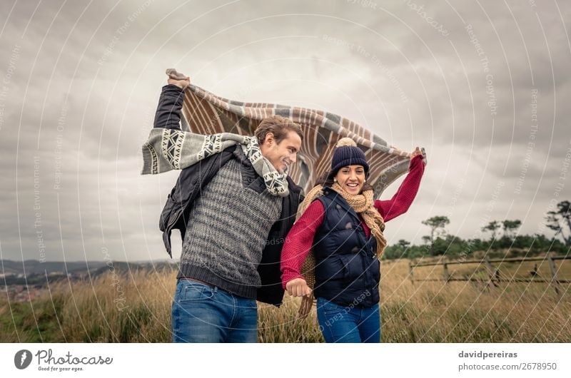 Young couple playing outdoors with blanket in a windy day Lifestyle Happy Beautiful Playing Ocean Winter Mountain Woman Adults Man Couple Nature Sky Clouds