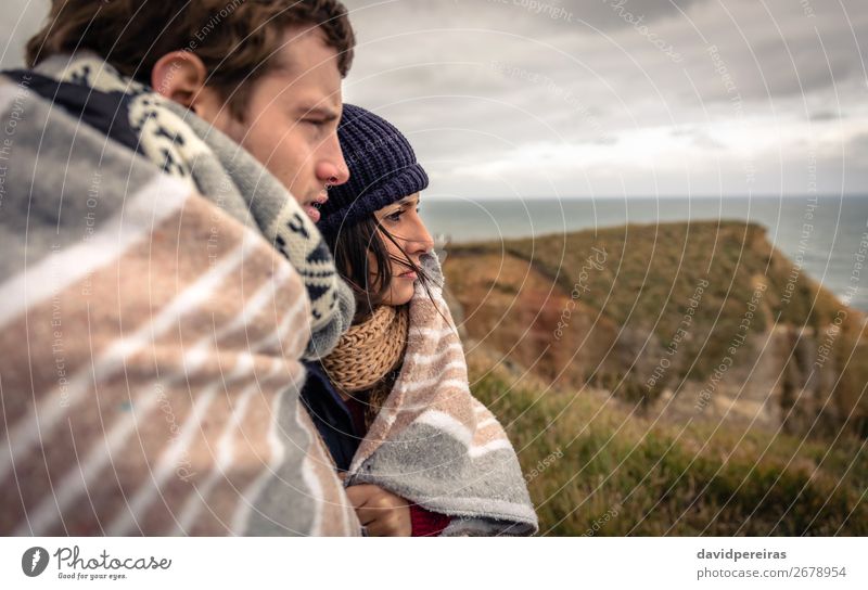 Young couple under blanket looking the sea with dark cloudy sky on background Lifestyle Beautiful Ocean Winter Woman Adults Man Couple Nature Sky Clouds Autumn