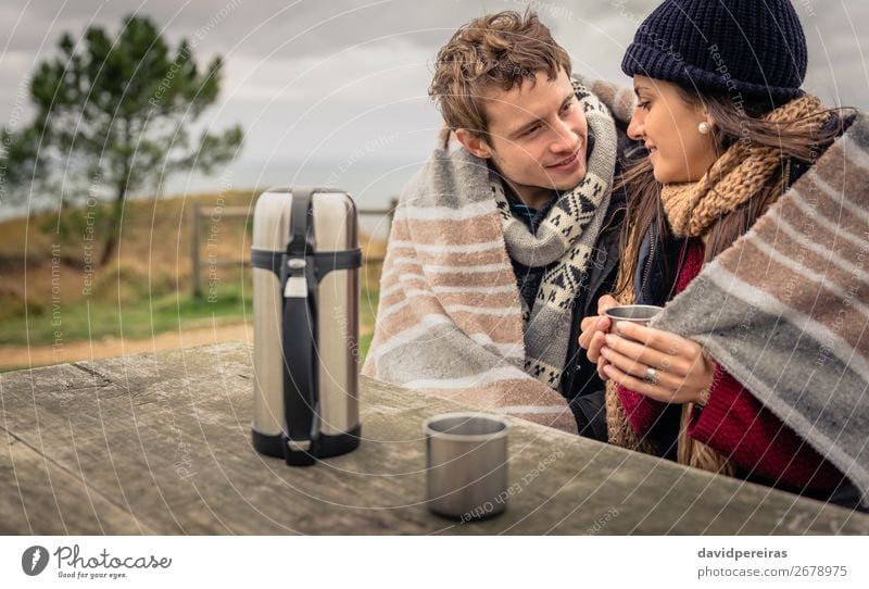 Young couple under blanket having hot drink in a cold day Beverage Coffee Tea Lifestyle Happy Winter Table Woman Adults Man Couple Hand Nature Sky Clouds Autumn
