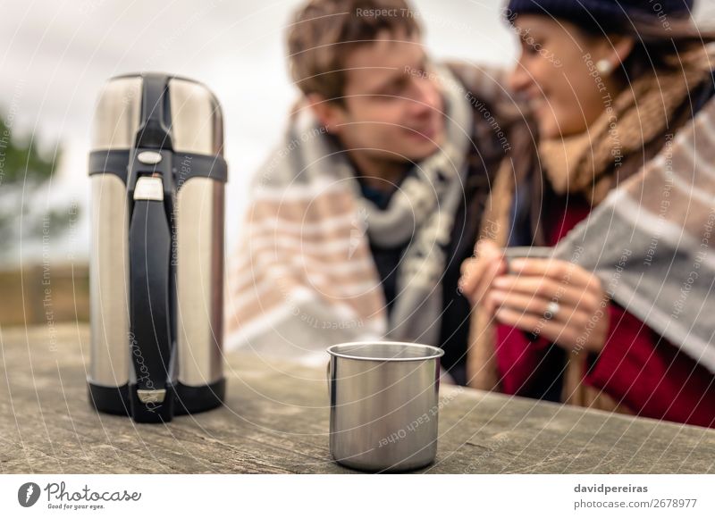 Cup and thermos in table with couple under blanket blurred on background Beverage Coffee Tea Lifestyle Happy Winter Table Woman Adults Man Couple Hand Nature