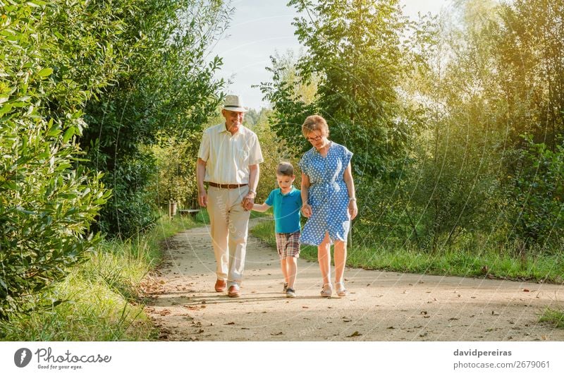 Grandparents and grandchild walking on nature Happy Leisure and hobbies Summer Child To talk Human being Boy (child) Woman Adults Man Grandfather Grandmother
