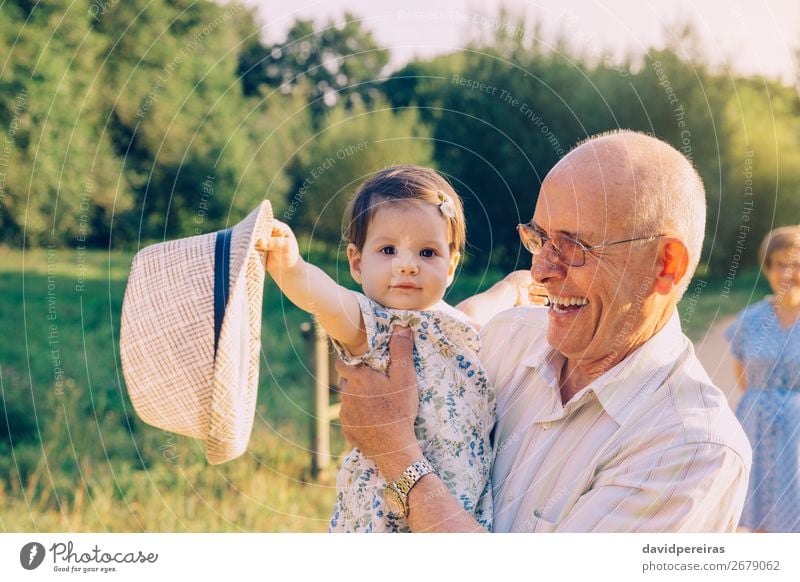 Baby girl playing with hat of senior man outdoors Lifestyle Happy Relaxation Playing Summer Human being Toddler Woman Adults Man Parents Grandfather
