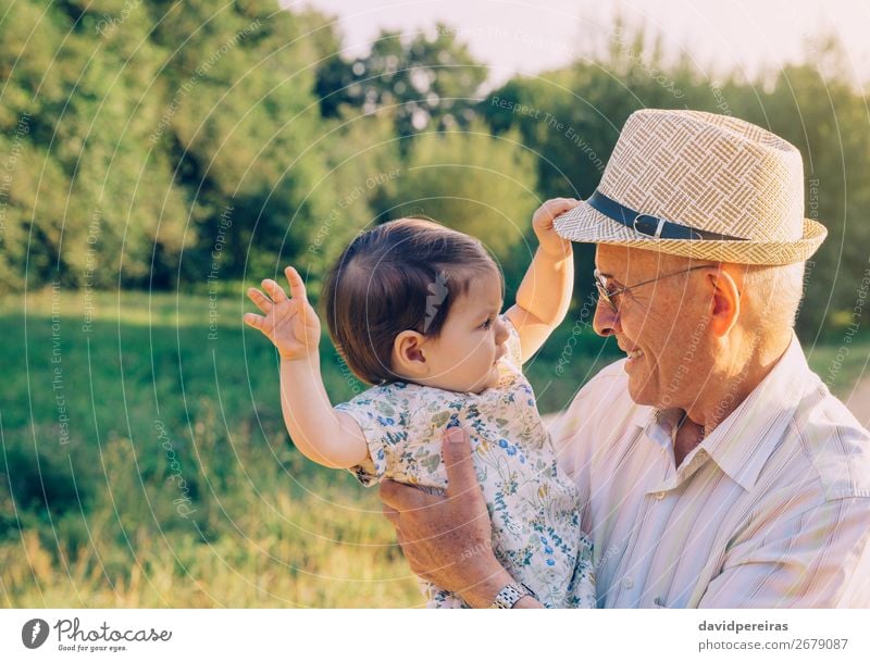 Baby girl playing with hat of senior man Lifestyle Happy Relaxation Playing Summer Human being Toddler Woman Adults Man Parents Grandfather Family & Relations