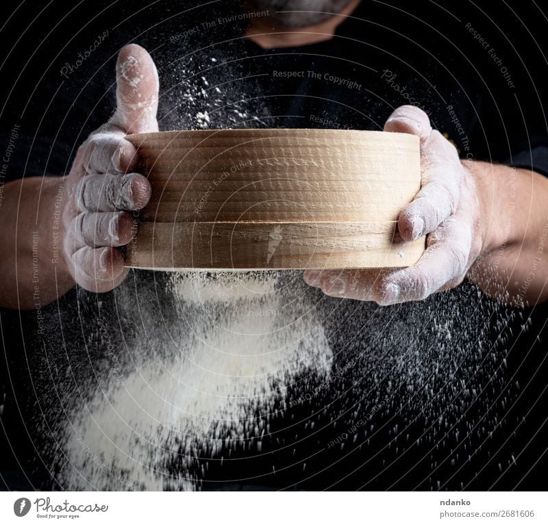 man sifts white wheat flour through a wooden sieve Dough Baked goods Bread Nutrition Kitchen Cook Human being Man Adults Hand Sieve Movement Make Fresh Black