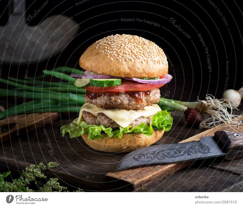 cheeseburger with vegetables Meat Cheese Vegetable Bread Roll Lunch Dinner Fast food Knives Table Restaurant Wood Dark Fresh Large Delicious Green Red Black