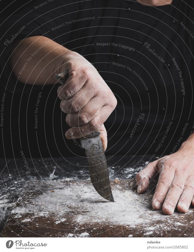 cook in black clothes holding a vintage old knife Dough Baked goods Bread Knives Table Kitchen Cook Human being Hand Fingers Wood Old Make Brown Black Bakery