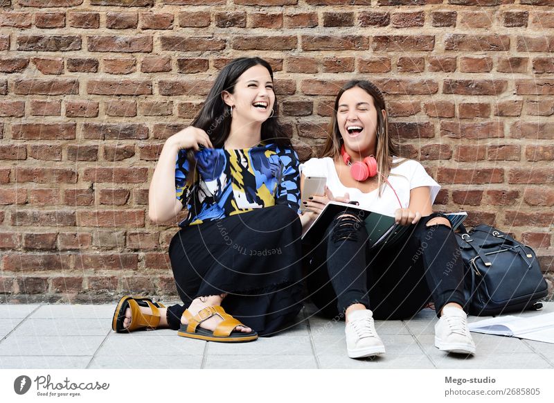 Young students laughing and studying Lifestyle Joy Happy Beautiful Academic studies To talk Telephone PDA Technology Woman Adults Friendship Group Book Smiling