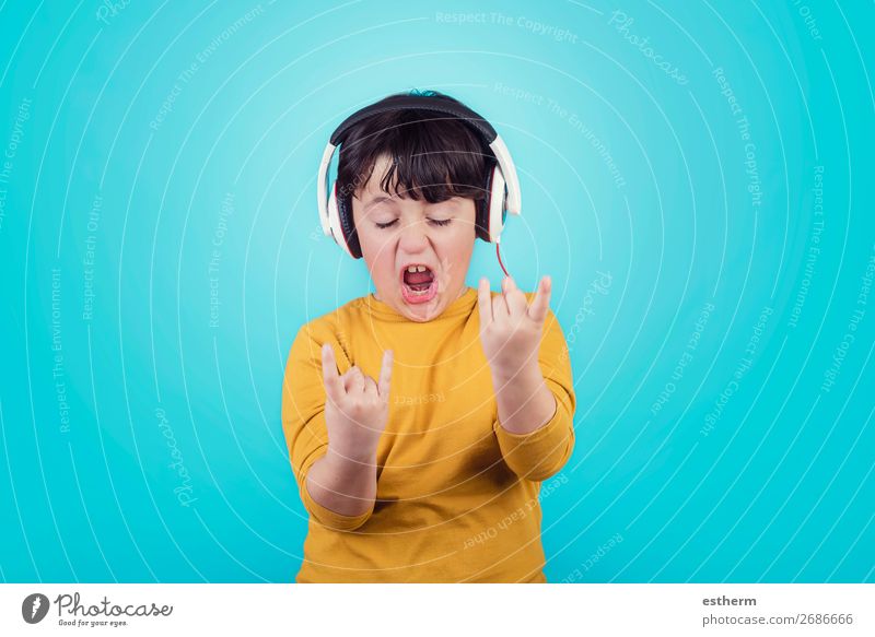 Boy with headphones showing rock sigh on blue background Lifestyle Joy Entertainment Music Human being Masculine Child Boy (child) Infancy 1 8 - 13 years