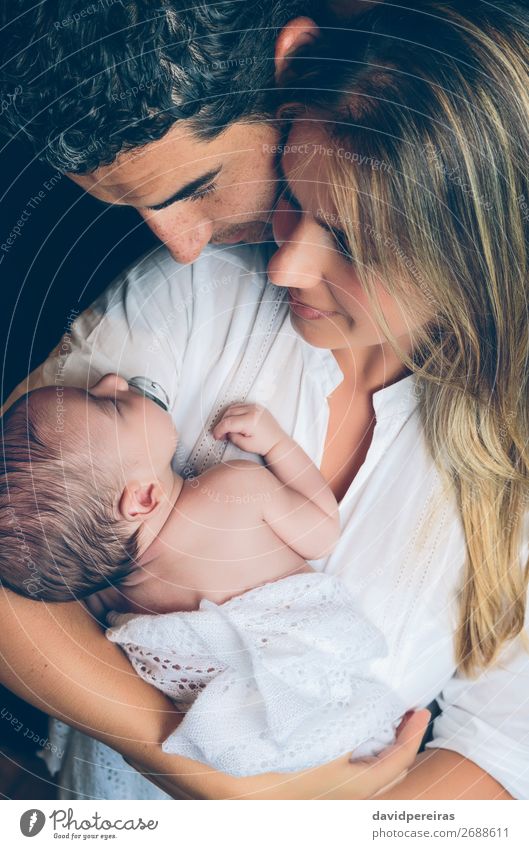 Couple embracing a newborn over dark background Lifestyle Happy Beautiful Child Human being Baby Toddler Woman Adults Man Parents Mother Father