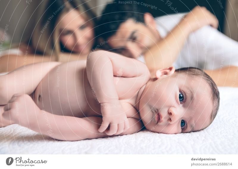 Newborn lying over bed and couple smiling on background Lifestyle Joy Happy Beautiful Leisure and hobbies Bedroom Child Human being Baby Toddler Boy (child)