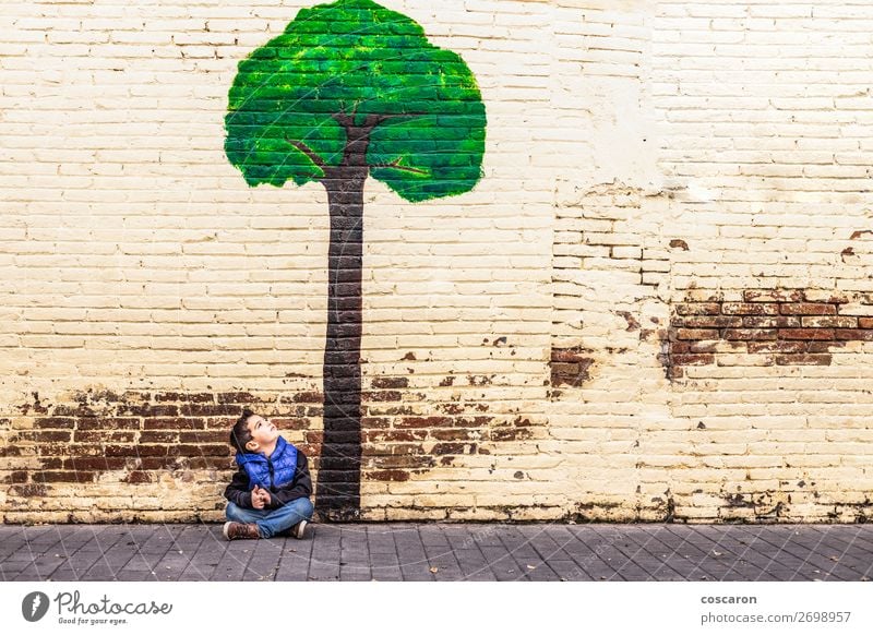 Little kid seated under a tree painted on a wall Joy Happy Beautiful Playing Vacation & Travel Tourism Adventure Summer Garden Climbing Mountaineering Education