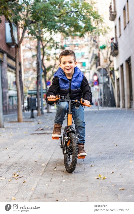 Little kid riding his bicycle on city street Lifestyle Joy Happy Beautiful Relaxation Leisure and hobbies Playing Children's game Sun Winter Sports Cycling