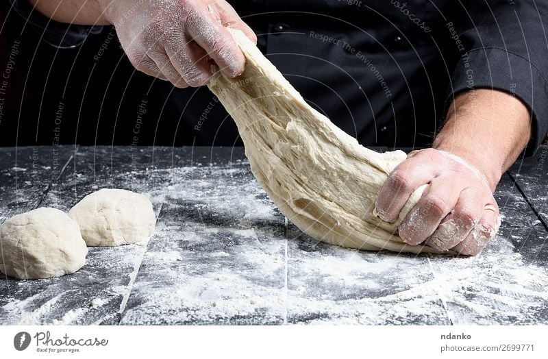 chef in black uniform kneads white wheat flour dough Dough Baked goods Bread Nutrition Table Kitchen Cook Human being Man Adults Hand Wood Make Fresh Black