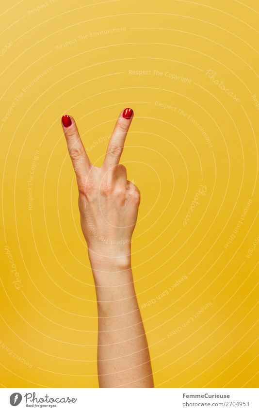 Hand signal for peace against a yellow background Feminine 1 Human being Communicate Peace Gesture Fingers Underarm Yellow Nail polish Red Symbols and metaphors