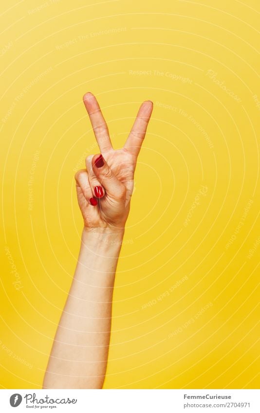 Hand signal for victory against a yellow background Feminine Woman Adults 1 Human being 18 - 30 years Youth (Young adults) 30 - 45 years Communicate Success