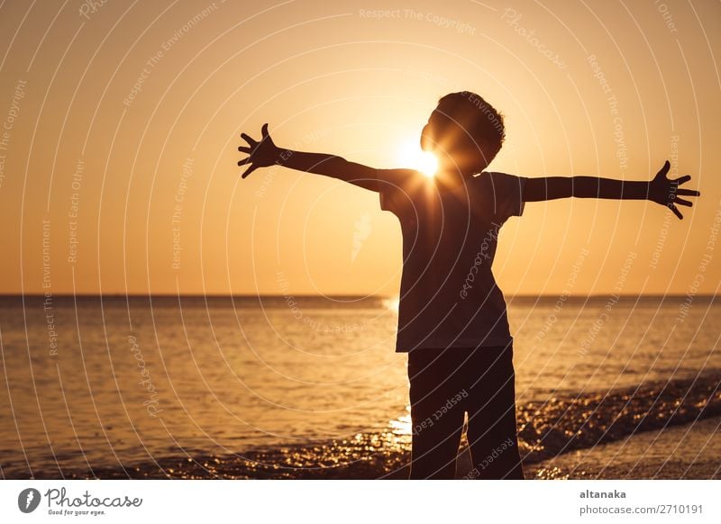 One happy little boy playing on the beach at the sunset time. Kid having fun outdoors. Concept of summer vacation. Lifestyle Joy Happy Beautiful Relaxation