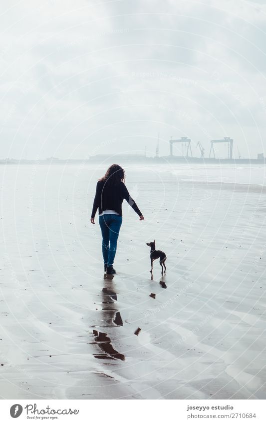 Woman and her small dog on the beach Lifestyle Relaxation Beach Winter Adults Friendship Nature Landscape Sand Horizon Bridge Jeans Brunette Dog Love Blue 1812