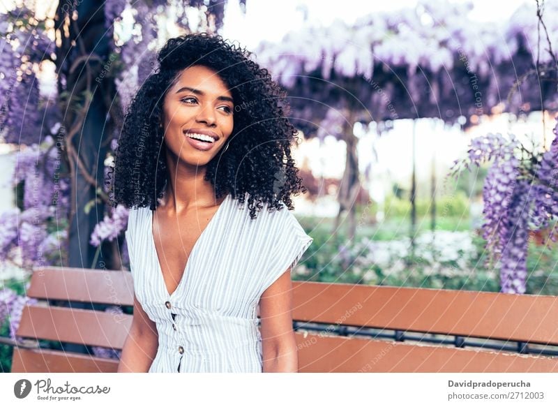 Happy young black woman sitting surrounded by flowers Woman Blossom Spring Lilac Portrait photograph multiethnic Black African Mixed race ethnicity Smiling