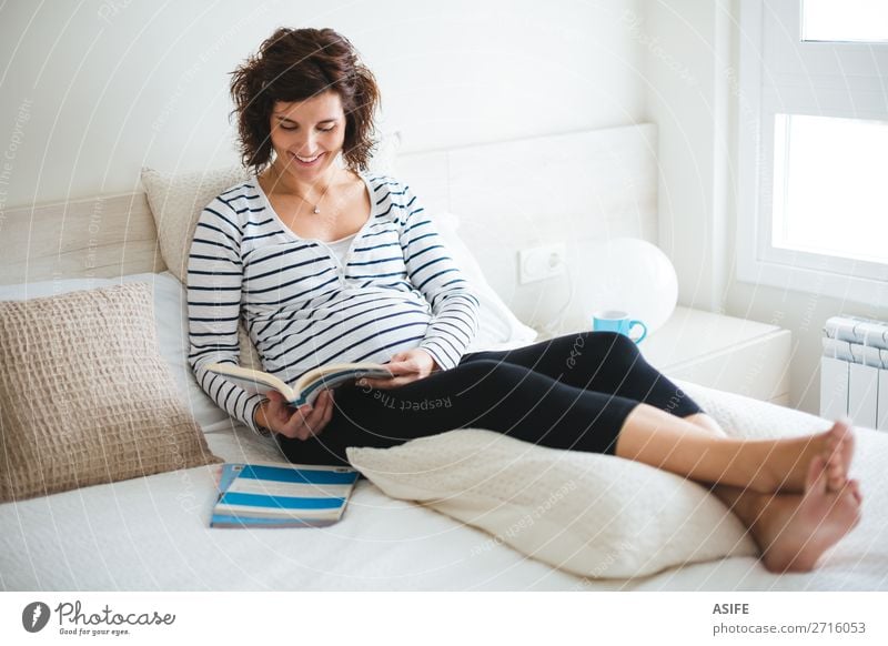 Happy pregnant woman reading on the bed Beautiful Body Relaxation Leisure and hobbies Reading Bedroom Baby Woman Adults Parents Mother Book Sit Pregnant Future