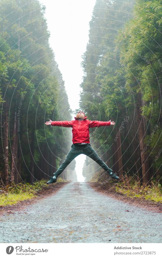 Man jumping on road in forest Tourist Nature bearded Jump Red Jacket Street Lanes & trails Forest Green Vacation & Travel Adventure Landscape Azores Hiking