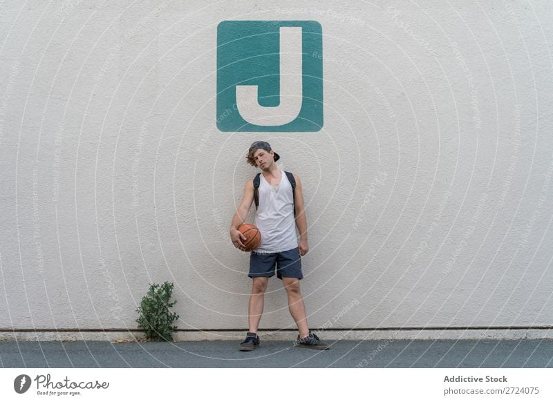 Man with basketball posing on wall Basketball Posture Street Sportswear Stand Lifestyle Relaxation Youth (Young adults) Self-confident Playing Ball Player