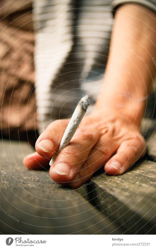 Hand holding a burning hand-rolled cigarette. Woman which sits smoking on a bench Roll-up cigarette Feminine Fingers Smoking Sit Authentic Relaxation To enjoy