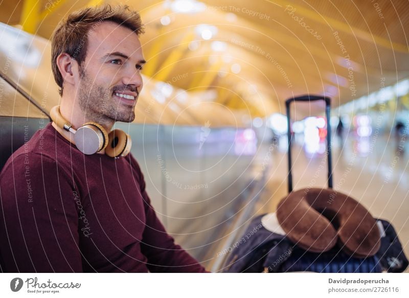 Young man waiting listening music and using mobile phone at the airport with a suitcase. Wait Airport Youth (Young adults) Smiling Caucasian Listening Music