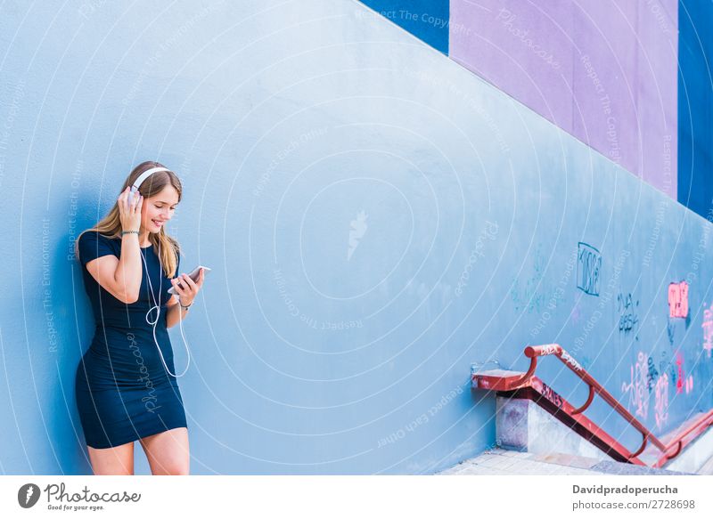 Happy young woman listening to music on the mobile phone by a colorful wall Woman Blonde Music Multicoloured Listening Telephone Wall (building) Mobile