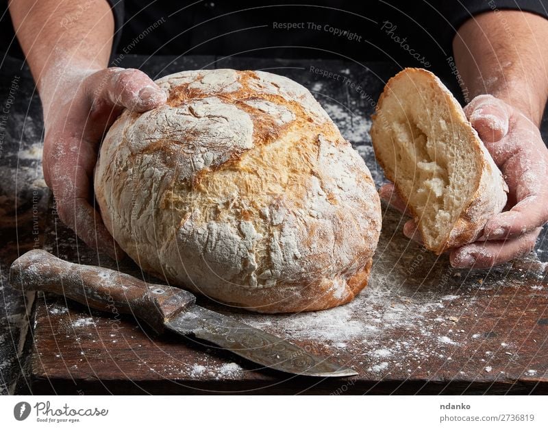 cook in a black tunic holds fresh baked bread Bread Nutrition Table Kitchen Cook Human being Hand Fingers Wood Eating Make Dark Fresh Brown Black White