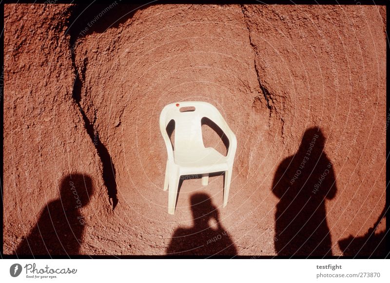a chair Human being 3 Earth Sand Whimsical Feces Plastic chair Garden chair Rock Red Shadow Shadow play Colour photo Exterior shot Detail Abstract Day Sunlight