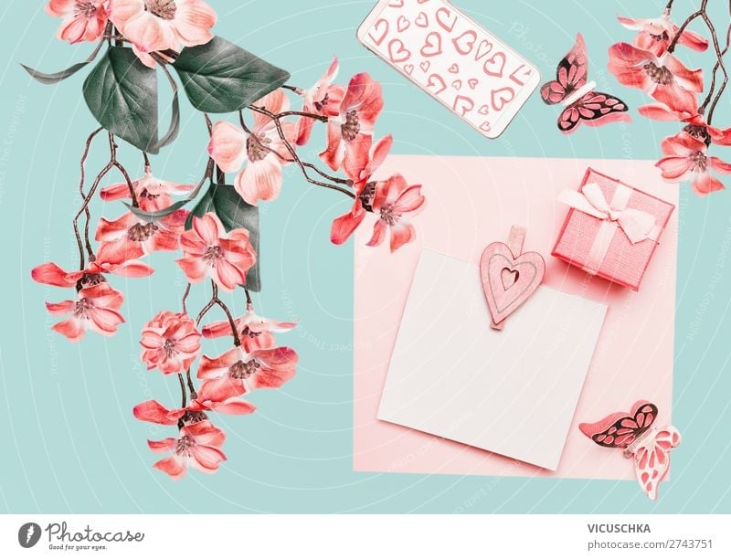 Beautiful floral composing with coral flowers blossom hanging branch on light turquoise. Floral layout beautiful coral color summer hipster background mint
