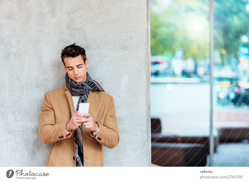 Stylish young man wearing denim clothes leaning on a wall Lifestyle Elegant Style Beautiful Hair and hairstyles Telephone PDA Young man Youth (Young adults) Man