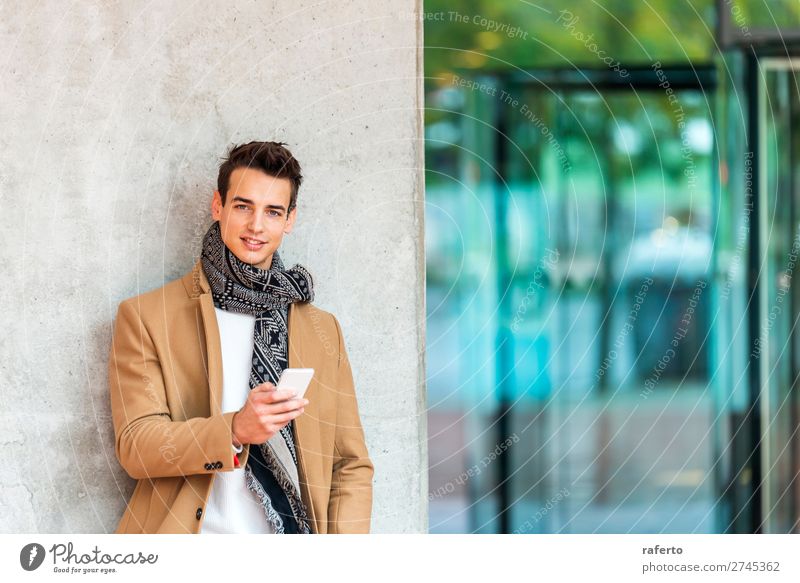 young man wearing denim clothes leaning on a wall while using a mobile phone outdoors Lifestyle Elegant Style Beautiful Hair and hairstyles Telephone Cellphone