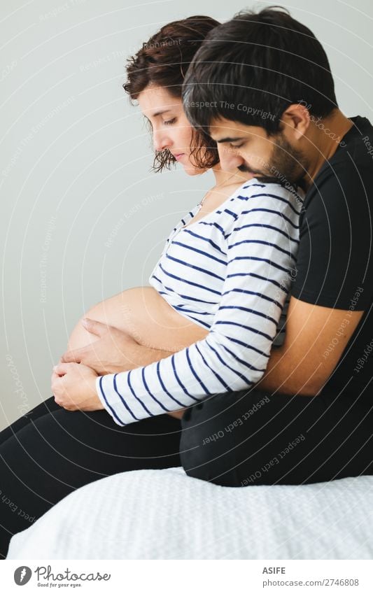 Loving pregnant couple sitting on the bed Happy Beautiful Body Baby Woman Adults Man Parents Mother Father Family & Relations Couple Touch Smiling Love Sit