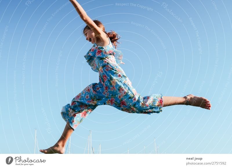 Young girl in jumpsuit with flower pattern jumps to the left in front of blue sky Athletic Playing Feminine Girl 1 Human being 8 - 13 years Child Infancy
