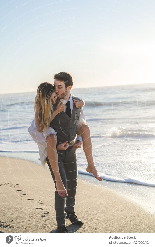 Groom carrying charming girl on back Couple Wedding Beach Summer Ocean in love Bride Carrying Relaxation Cheerful Dress Beautiful Nature Engagement Together