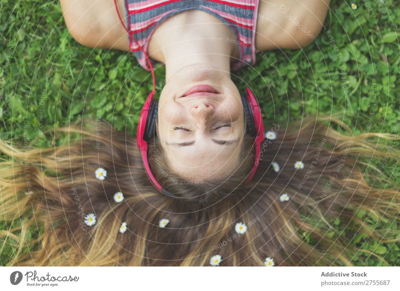 Excited girl in headphones on grass Woman Expressive Headphones Posture Grass Lie (Untruth) Park facial Flower Excitement Model Expression Style