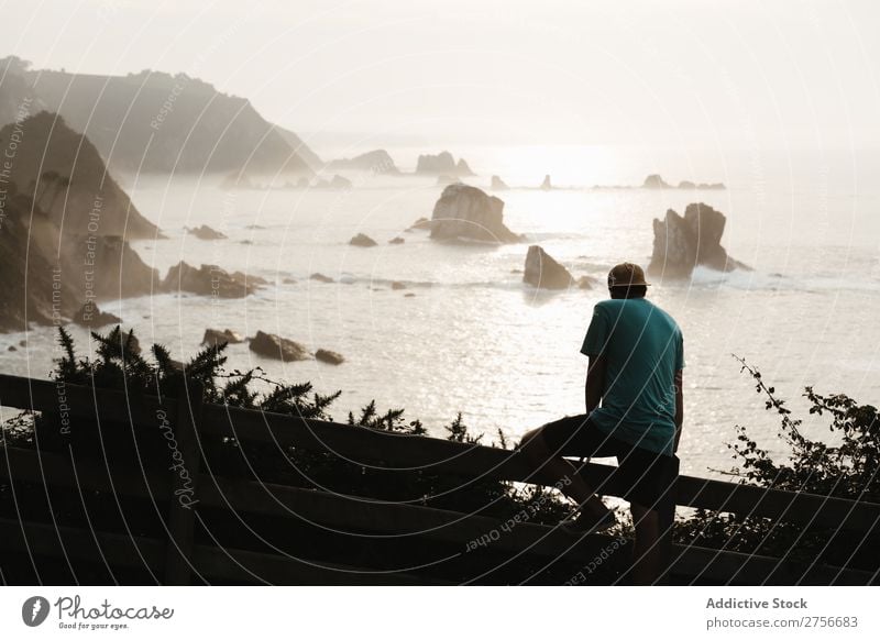 Man sitting on fence in rocky coast Fence Cliff Ocean Rock Vacation & Travel Tourism Nature Landscape Coast Water Sun Freedom Stone Natural Lifestyle Beautiful