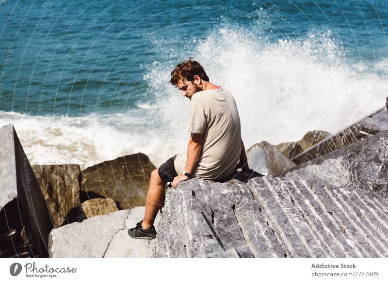Man sitting on stones at sea Ocean Sit Waves Stone Splashing tides Water Human being Nature Youth (Young adults) Loneliness Vacation & Travel Coast