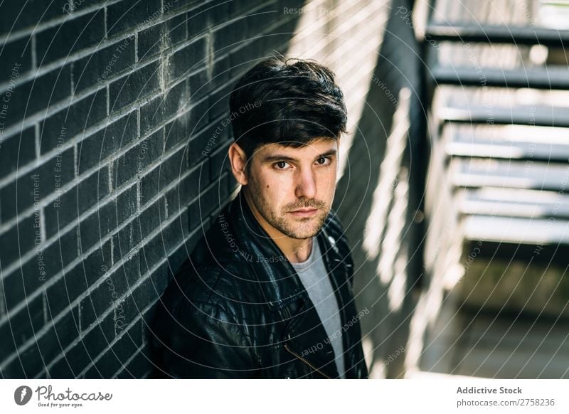 Young pensive man near fire stairs stylish thoughtful looking at camera sitting confident young cool person portrait modern model fashionable male serious