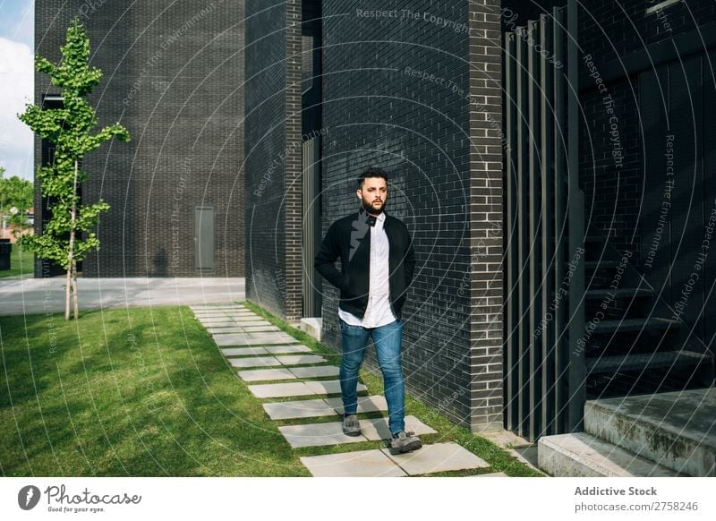 Trendy young man walking in the street looking away thoughtful pensive stylish brick wall standing confident cool person portrait modern model fashionable male