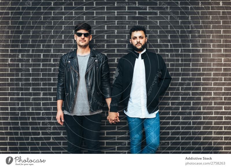 Gay couple holding hands Couple Stand Wall (building) Brick Looking into the camera Posture Homosexual In pairs Man Love 2 Together Lifestyle Relationship
