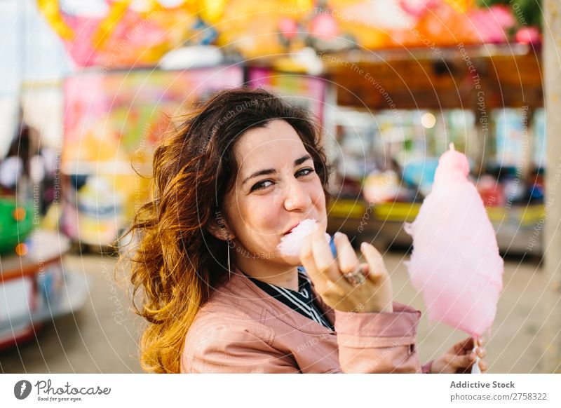 Woman with cotton candy in the park woman merry-go-round person pink female pretty sweet food eat sugar fun lifestyle portrait young smile holding snack outside
