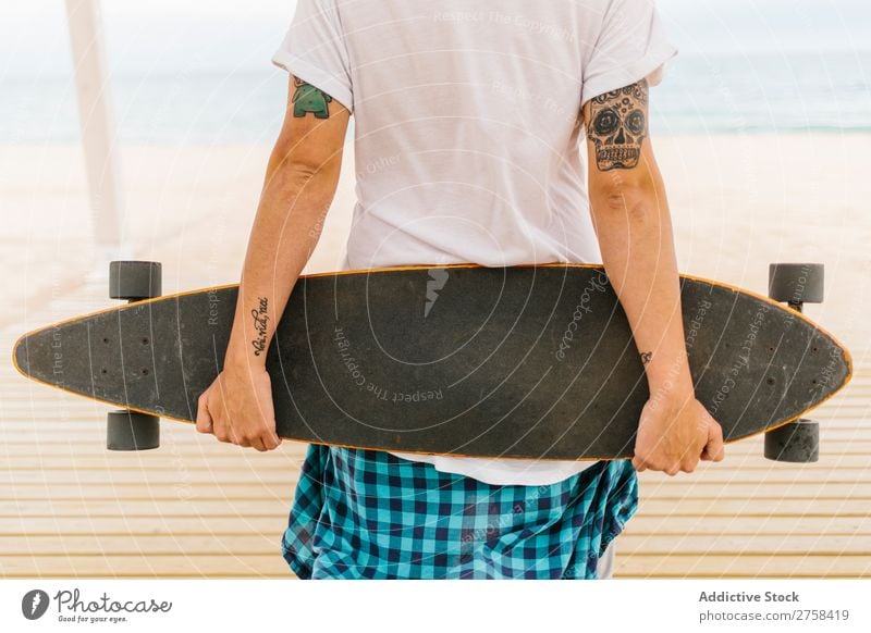 Tattooed man holding skateboard Skateboard Coast Beach Man Leisure and hobbies Multicoloured youngster Action Youth (Young adults) Sports Ice-skates