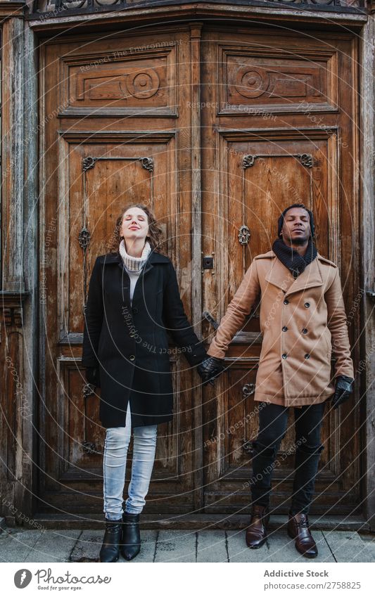 Couple holding hands at vintage door multiethnic Style Street warm clothes eyes closed Wood Door grungy Old Easygoing Beautiful Mixed race ethnicity Black