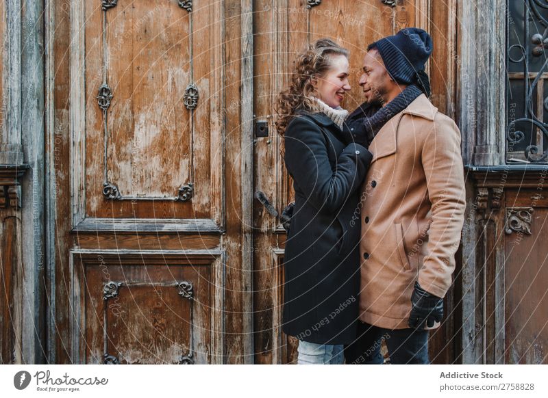 Couple embraced at vintage door multiethnic Style Street warm clothes Wood Door grungy Old Easygoing Beautiful Mixed race ethnicity Black Youth (Young adults)