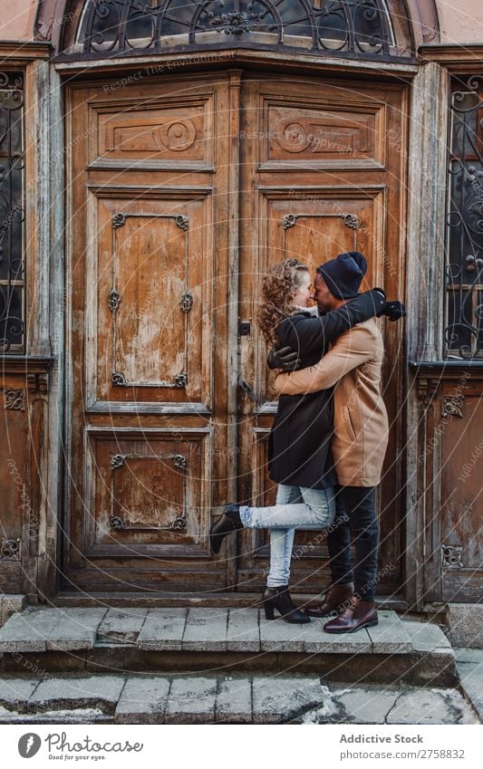 Couple embraced at vintage door multiethnic Style Street warm clothes Wood Door grungy Old Easygoing Beautiful Mixed race ethnicity Black Youth (Young adults)