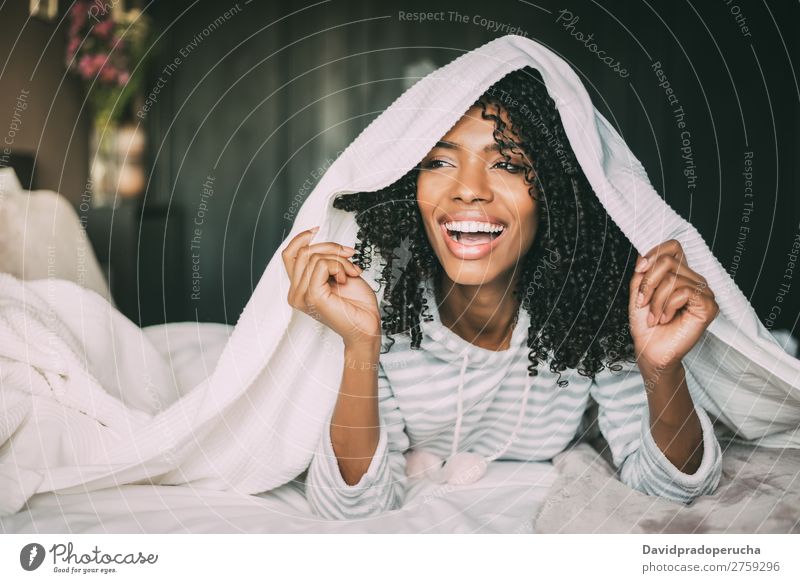 close up of a pretty black woman with curly hair smiling and covering with sheets on bed looking away Woman Bed Portrait photograph Close-up Sheet Covering