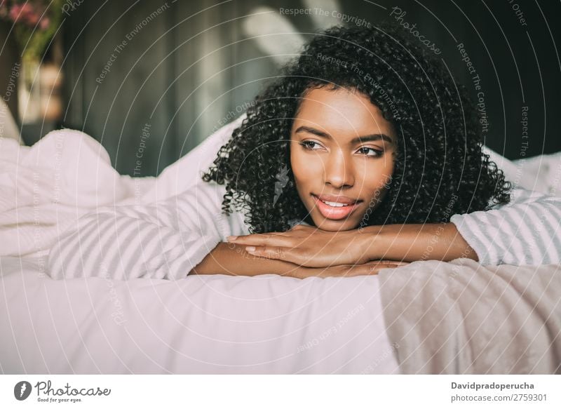 close up of a pretty black woman with curly hair smiling and lying on bed looking away Woman Bed Portrait photograph Close-up Lie (Untruth) Black Smiling